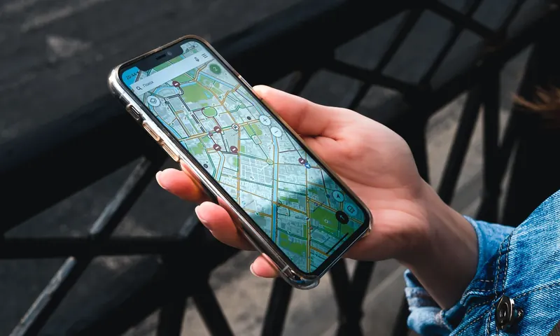 Рука тримає смартфон з відкритою картою міста на вулиці